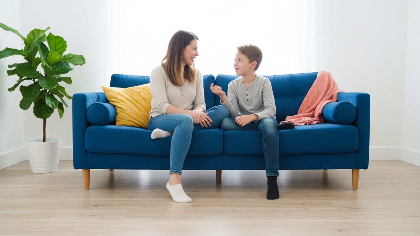 A parent and child grinning at each other during a talking game on a bright sofa